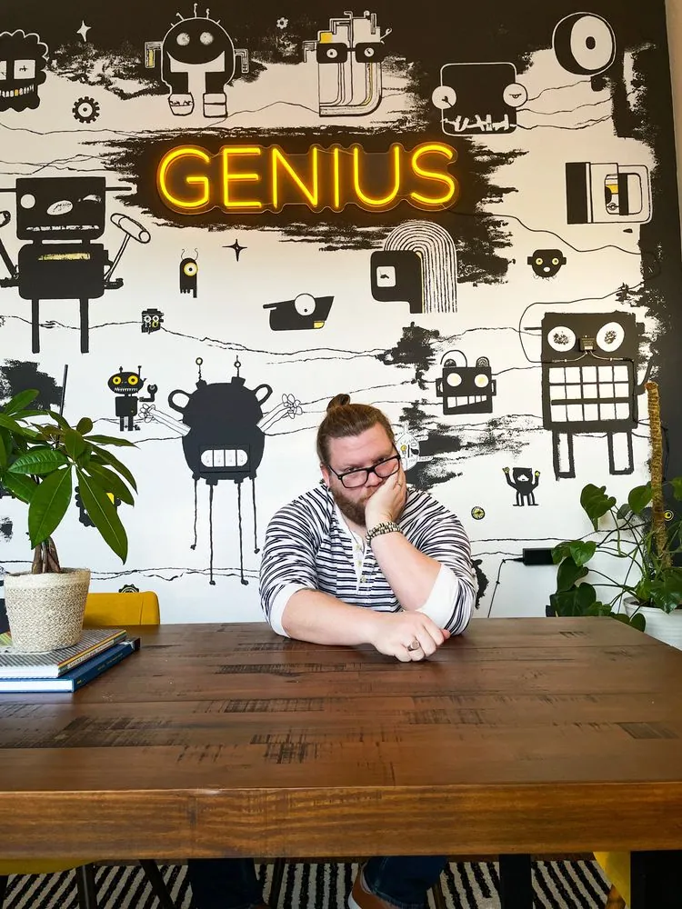Team member under the neon Genius sign